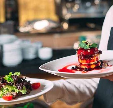 Waitress carrying 2 plates of food in a restaurant